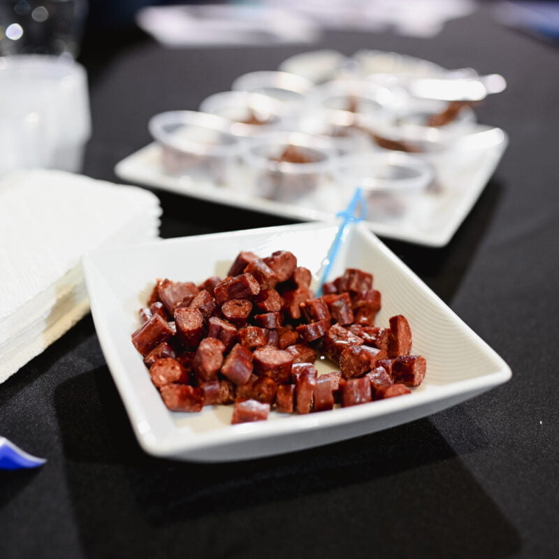 Saucisson de loup marin au algues dans un bol carré avec en fond des petits conteneurs en plastique pour goûter et déguster.