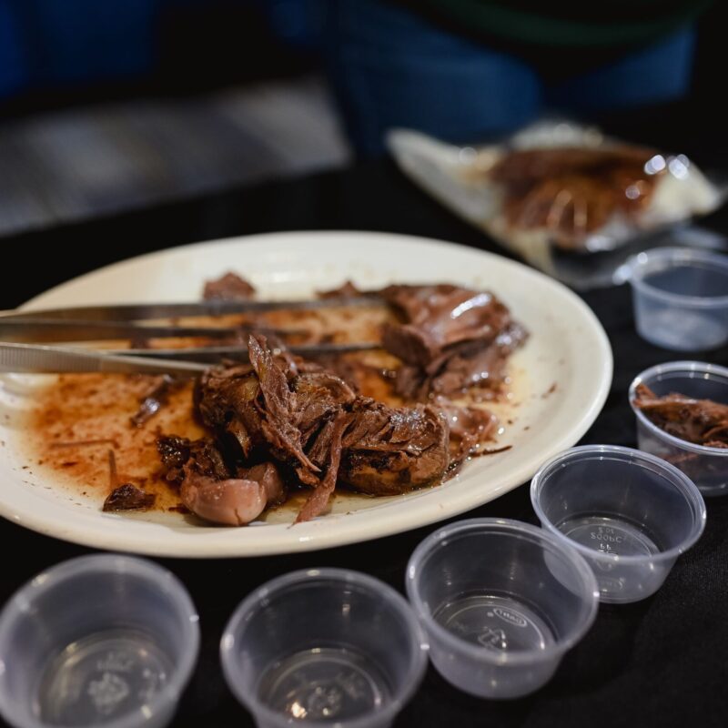 Assiette blanche avec de l'épaule de phoque confite au gras de canard, entourée de petits conteneurs plastiques pour tester et déguster.