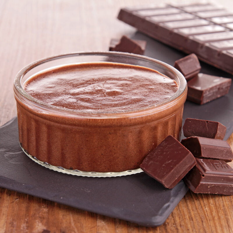 Photographie d'une verrine remplis de mousse au chocolat, posée sur une ardoise, avec une tablette de chocolat à côté.