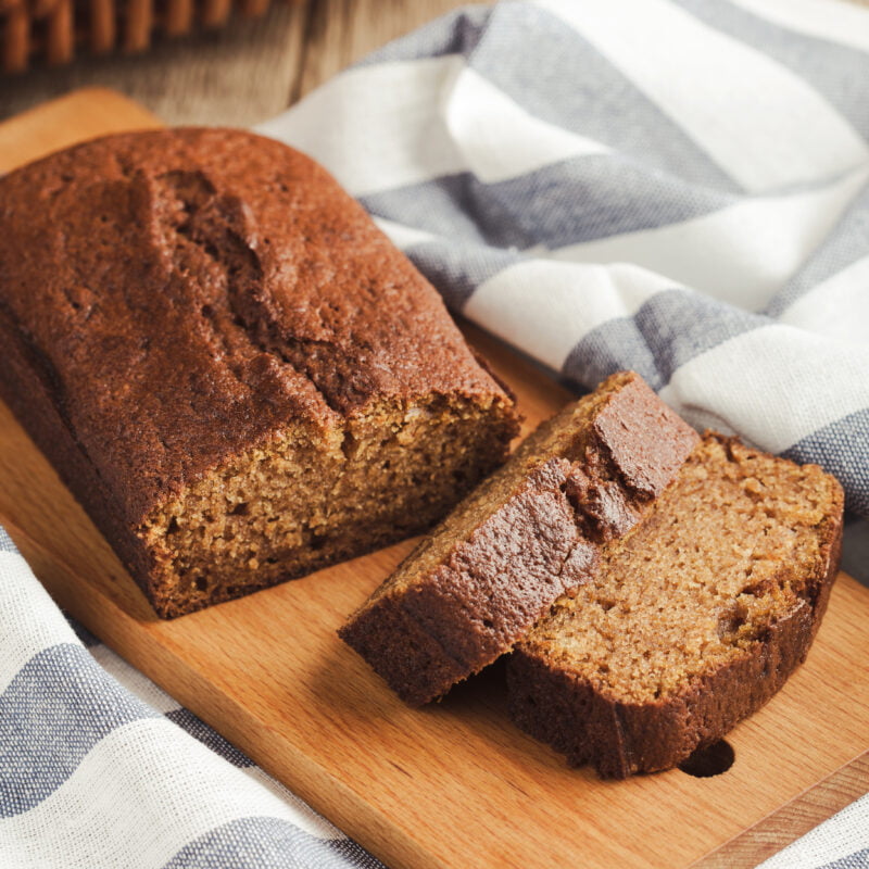 Photographie d'un cake avec deux tranches coupées, posé sur une planche en bois.