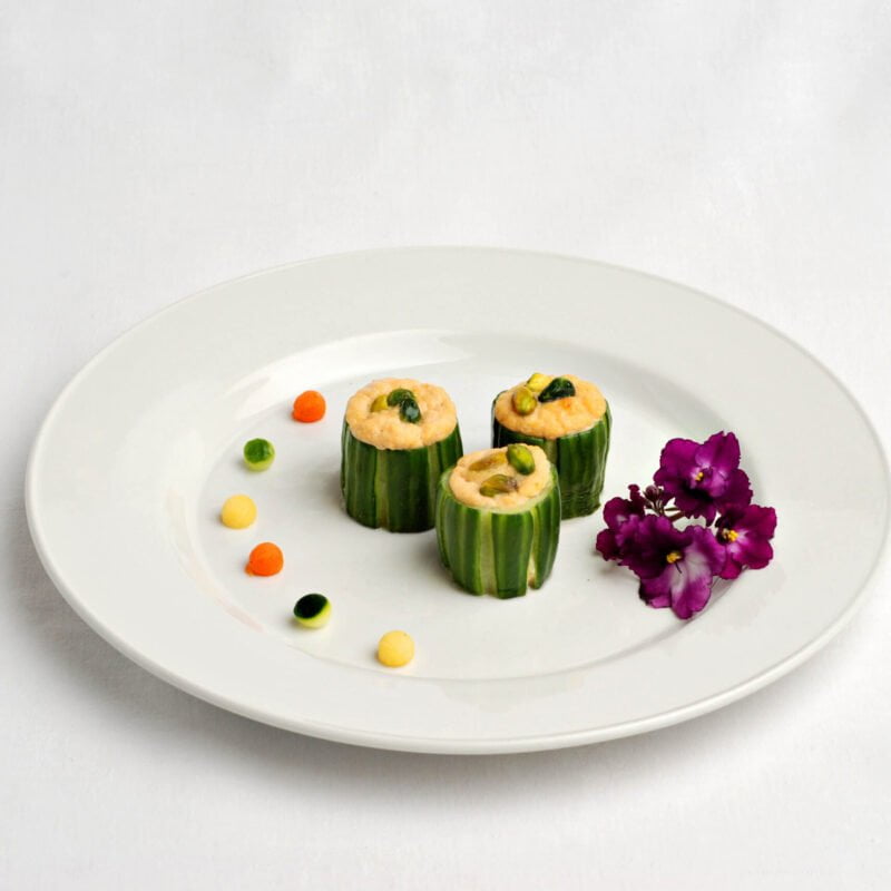 Concombre farci à la mousse de plie grise et pistaches avec petits légumes et fleur comestible.